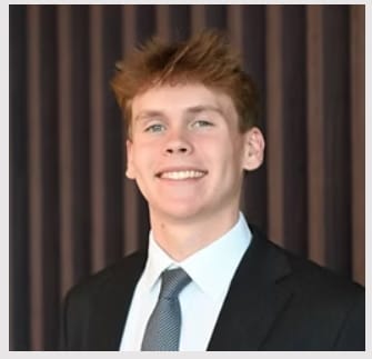 Aidan Kepuraitis, founder of The Foothold Project, smiling in a dark suit and tie